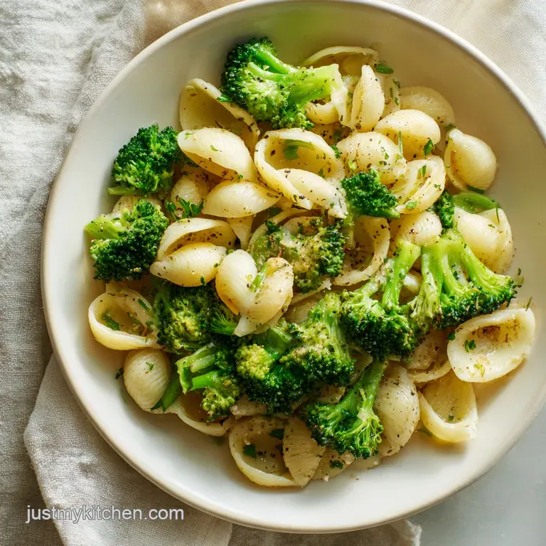 Elegantly swirled creamy pasta with bright green broccoli florets and a sprinkle of black pepper on a white plate.