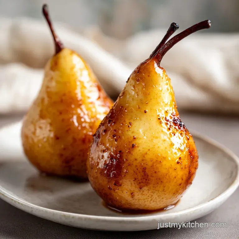 Buttery, soft pear dessert drizzled with rich caramel, dusted with powdered sugar and artistically plated on a white dish.