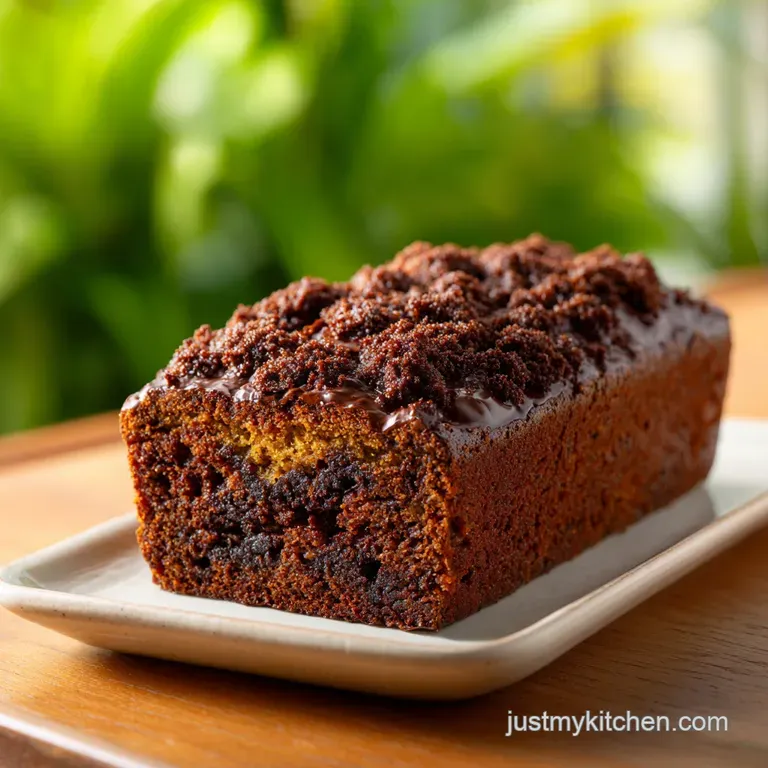 Slices of moist chocolate zucchini bread with powdered sugar. Dark chocolate chips and zucchini flecks add texture on a pl...
