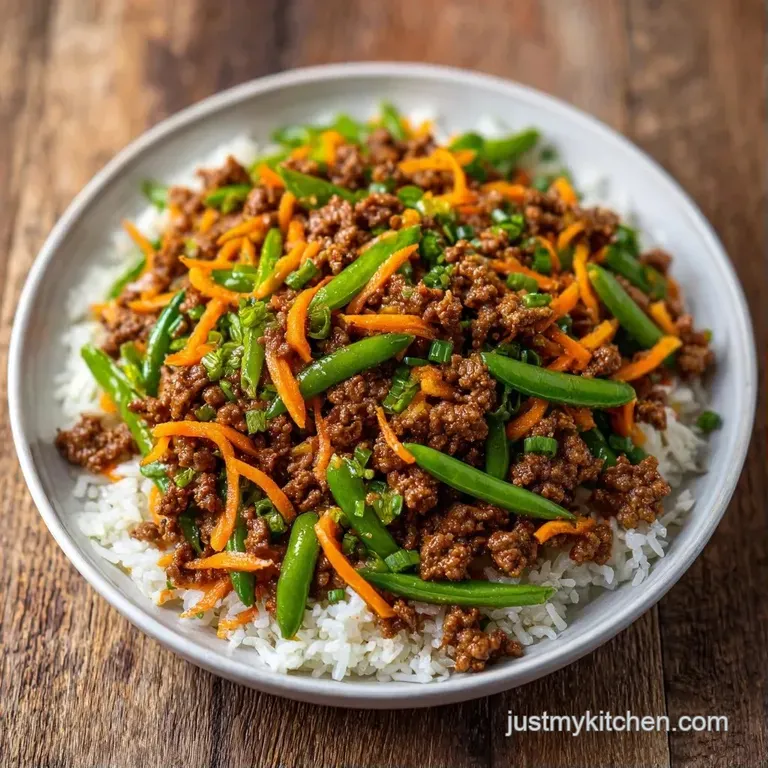 Saut&eacute;ed beef crumbles over a mound of pearly white rice in a modern bowl, topped with vivid green onion curls.