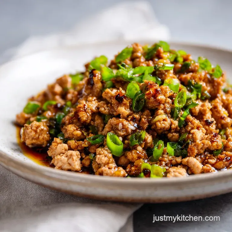 Glossy, dark honey garlic ground turkey served over fluffy white rice, garnished with bright green scallions on a white pl...