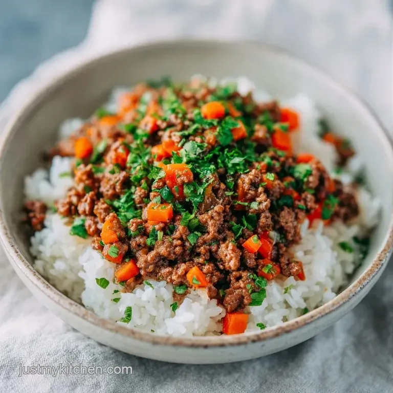 A neat mound of browned meat and fluffy grains topped with fresh green parsley on a matte white ceramic plate.