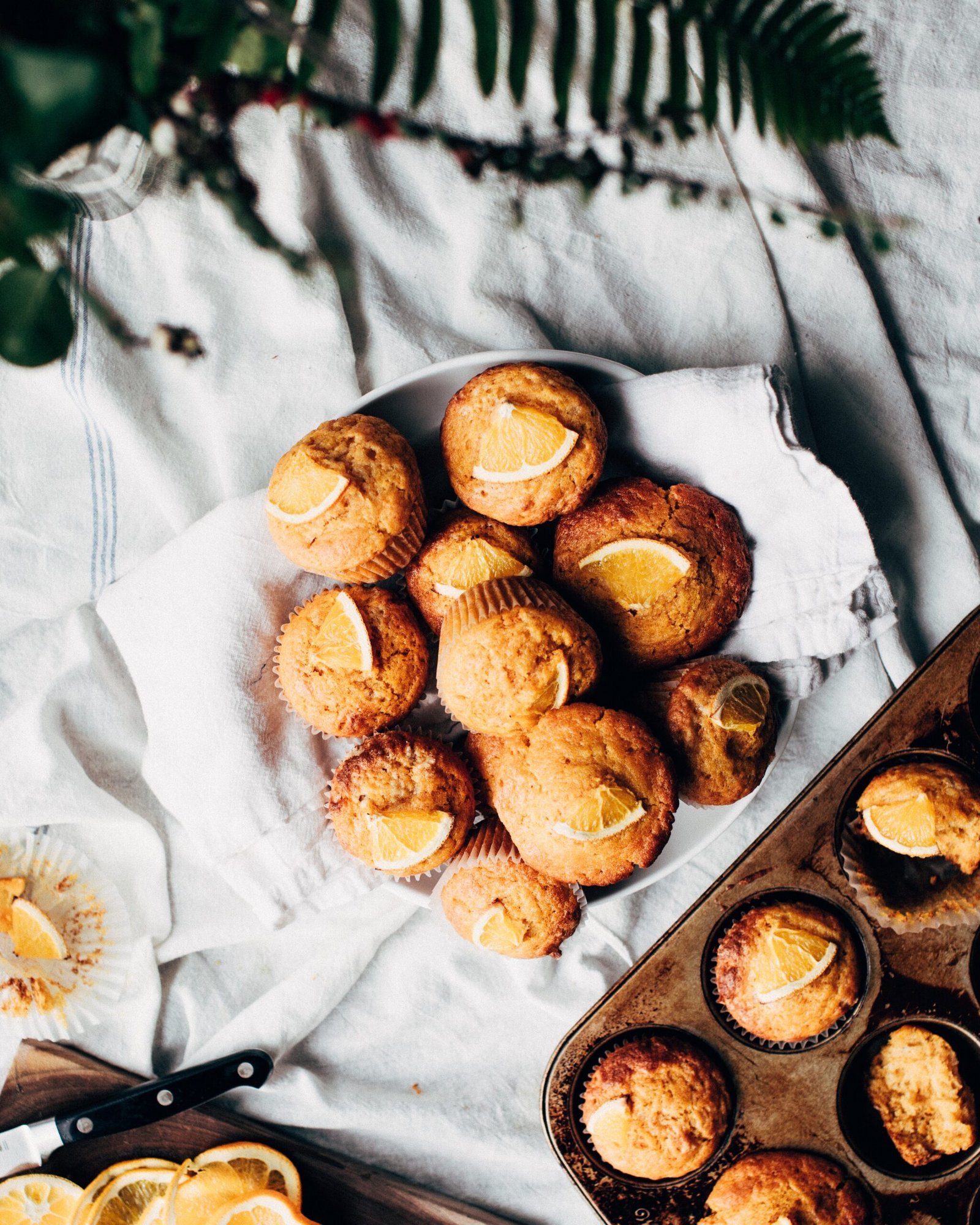 A tray of freshly baked pumpkin muffins topped with a sprinkle of cinnamon and served with a side of mini pumpkins.